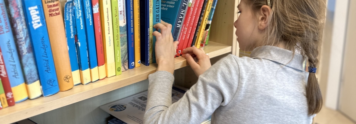 Mädchen am Bücherregal in der Schulbibliothek
