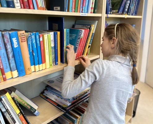 Mädchen am Bücherregal in der Schulbibliothek